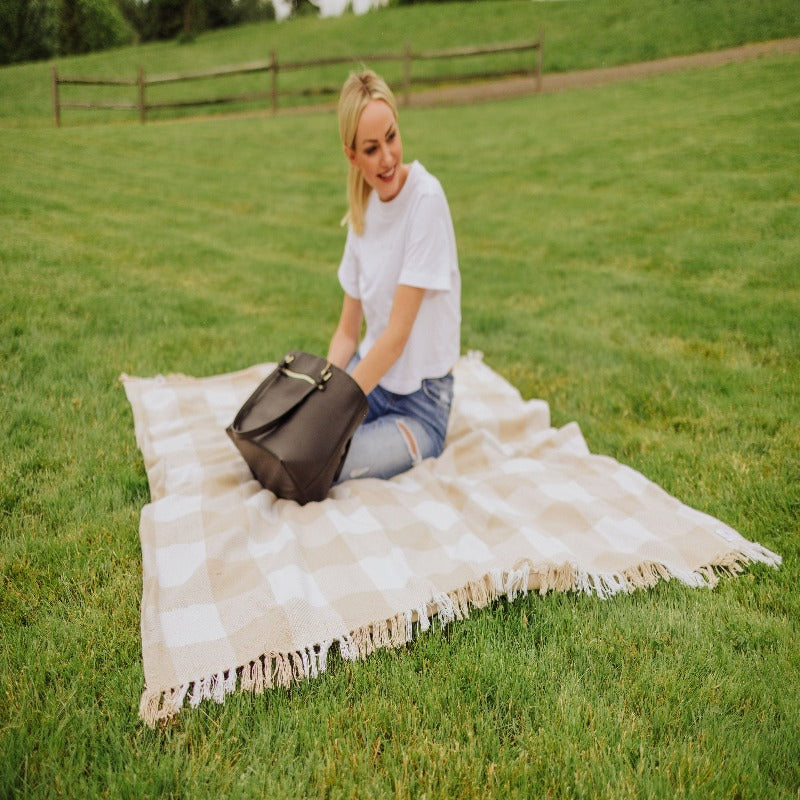 Picnic Time Montecito Picnic Blanket with Harness - Beige Gingham - woman sitting on blanket on grass