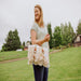 Picnic Time Montecito Picnic Blanket with Harness - Beige Gingham - woman carrying blanket by its harness