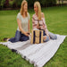 Picnic Time Montecito Picnic Blanket with Harness - White & Blue Stripe - two women enjoying wine sitting on lbanket