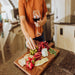 Toscana Madera Rectangular Charcuterie Board - woman holding wine glass with appetizers on board